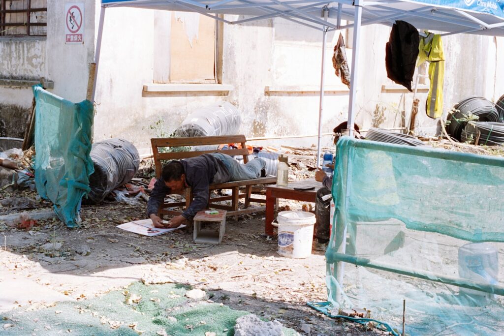 Man lying down drawing on paper under tent